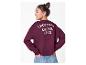 Fille en sweat-shirt bordeaux avec 'CROISSANT & COFFEE CLUB' au dos, mains dans les poches de son jean.