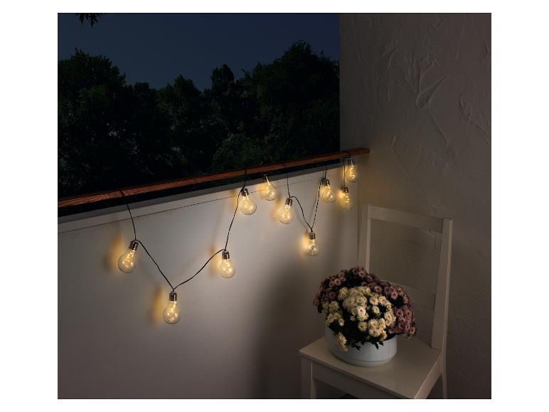 Une guirlande lumineuse avec des ampoules, suspendue à un balcon.