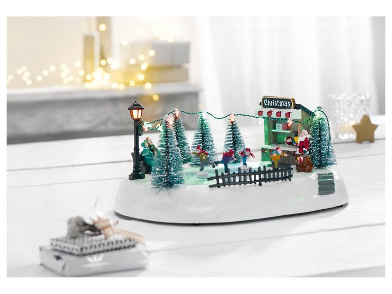 Scène de Noël avec patinoire, Père Noël et lumières festives sur une table blanche.