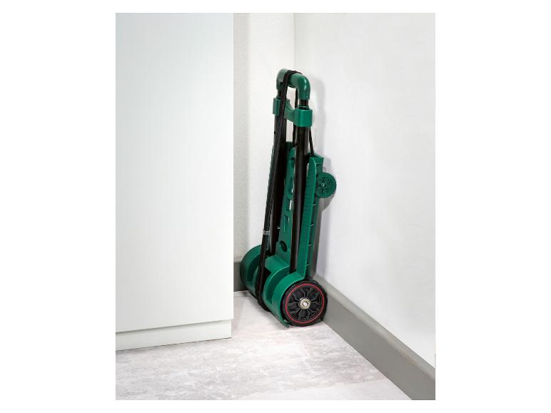 Chariot de transport vert plié, posé dans un coin de pièce.