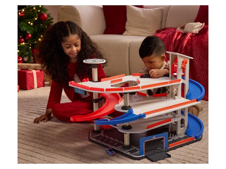 Deux enfants jouent avec un garage de jouet en bois à plusieurs niveaux.