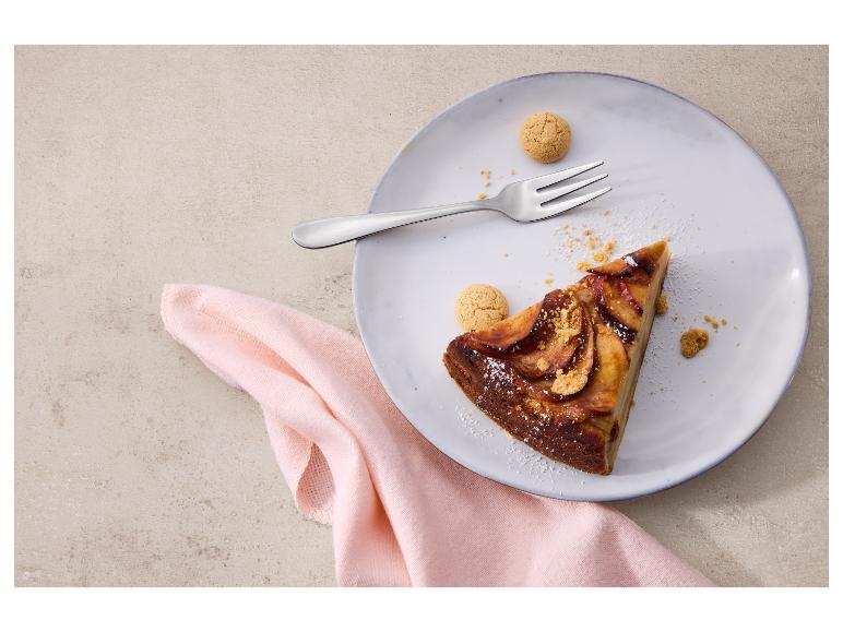 Une part de tarte aux pommes avec une fourchette et des biscuits sur une assiette, sur une serviette rose.