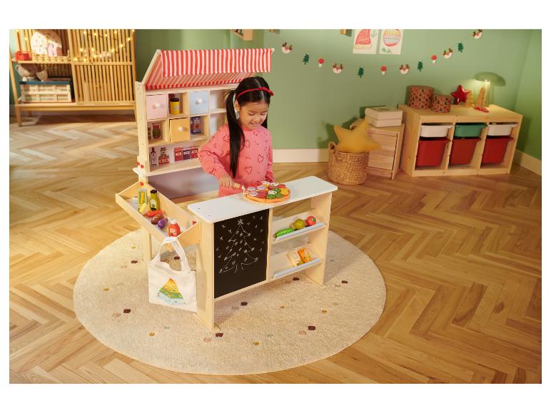 Un enfant joue avec le set d'aliments en bois LUPILU® sur un étal de marché en jouet.
