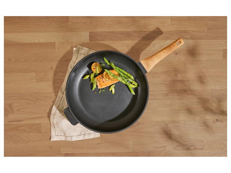 Poêle avec saumon, asperges et citron sur une table en bois.