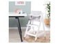 Une chaise haute blanche avec un coussin gris et une table à côté.