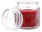 Bougie parfumée rouge dans un pot en verre nervuré avec couvercle ouvert.
