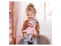 Fillette souriante tenant une poupée bébé vêtue de rose avec un bonnet.