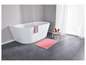 Un tapis de bain rose dans une salle de bain avec une baignoire blanche.