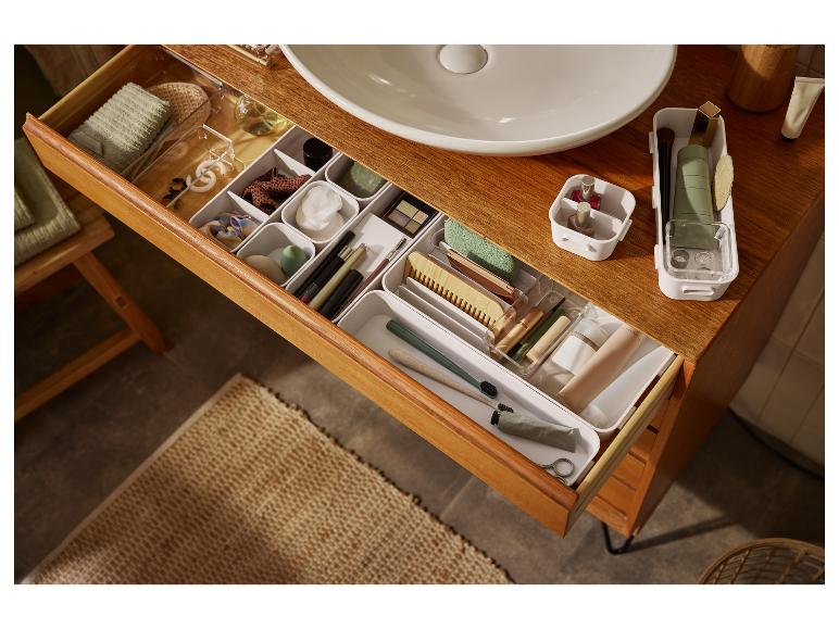 Rangement organisé de cosmétiques et articles de toilette dans une commode en bois.