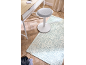Tapis bleu clair à motifs sur parquet avec un bureau et un tabouret blancs.