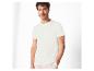 Homme en t-shirt blanc et pantalon beige, posant la main dans la poche.
