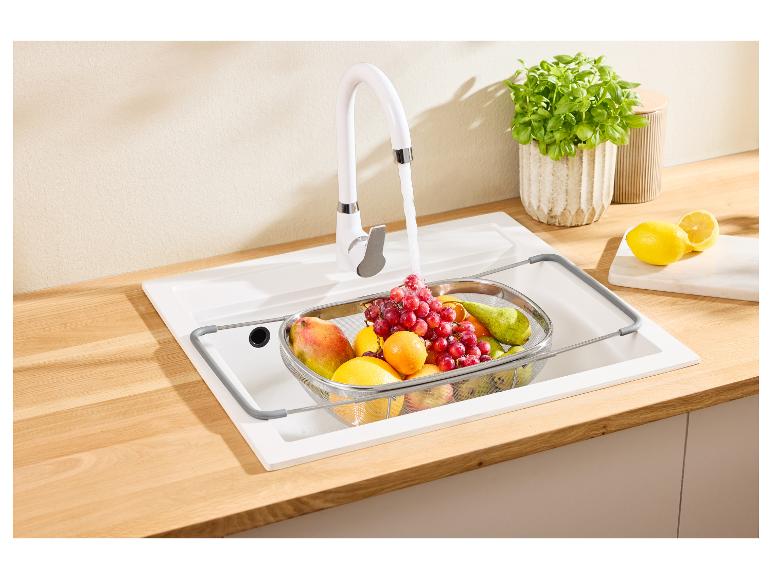 Robinet de cuisine blanc avec des fruits dans une passoire dans l'évier et des citrons sur le comptoir.