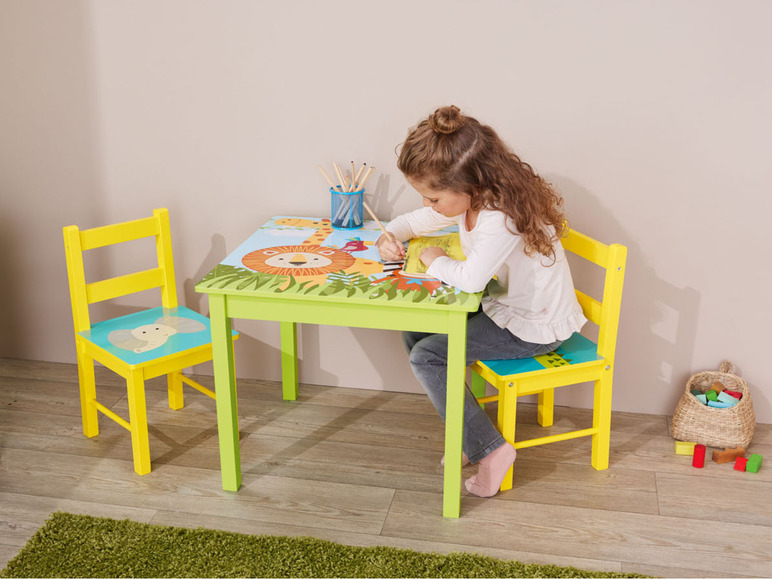 Un enfant assis à une table et une chaise sur le thème de la jungle.