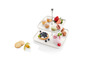 Un plateau de service à deux étages avec des pâtisseries, des macarons, des fruits et du yaourt.