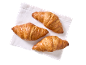 Trois croissants dorés sur une serviette blanche, vus d'en haut.