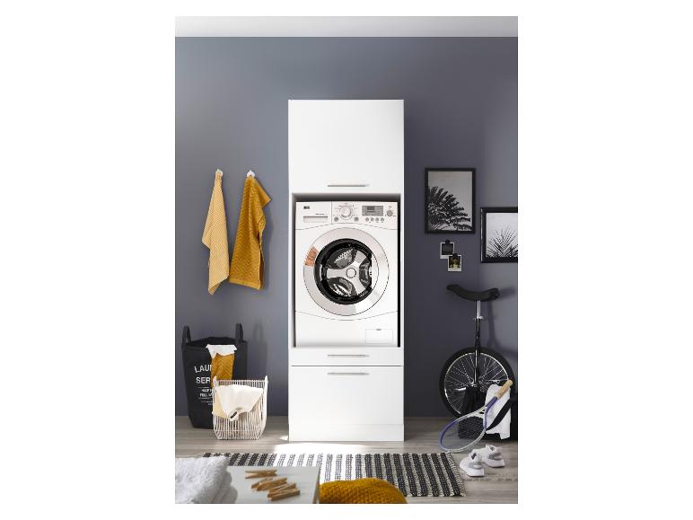 Lave-linge dans une armoire blanche, avec des paniers à linge et des équipements sportifs à côté.