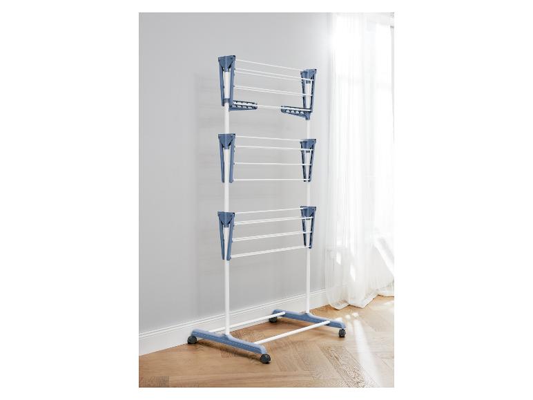 Séchoir à linge sur roulettes, bleu et blanc, près d'une fenêtre