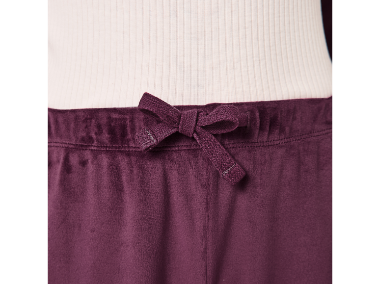 Pantalon en velours violet foncé avec cordon de serrage à la taille, combiné à un haut blanc côtelé.