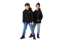 Deux enfants en doudounes noires, jeans et bottes d'hiver, souriant à la caméra.