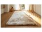 Un tapis beige clair et moelleux sur un sol en bois.