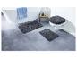 Deux tapis de bain gris et un tapis de toilette.