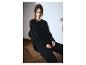 Femme en sweat-shirt et pantalon de jogging noirs, assise sur une chaise.
