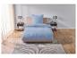 Un lit avec une couette et des oreillers bleu clair sur un tapis.
