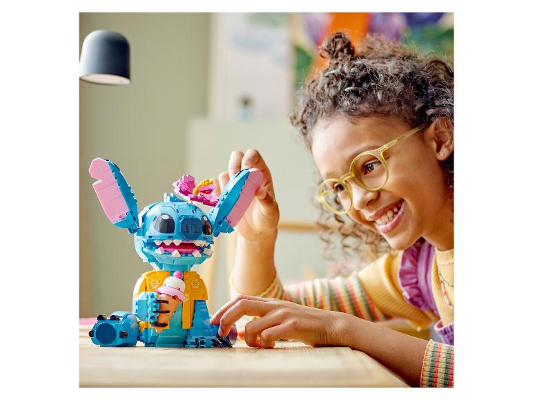 Enfant souriant jouant avec une figurine LEGO Stitch tenant une glace.