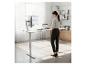 Femme travaillant à un bureau réglable en hauteur avec un moniteur et un ordinateur portable dans un bureau lumineux.