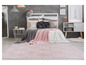 Un tapis rose avec un motif blanc devant un lit avec des couvertures