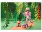 Fille avec casque sur trottinette et peluche dans une jungle en papier.