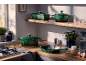 Batterie de cuisine en fonte verte sur un plan de travail et une étagère en bois.