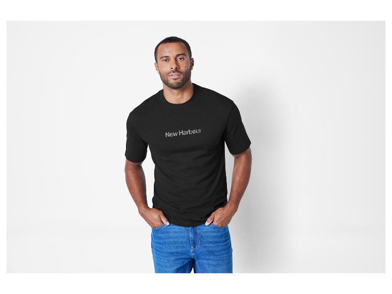 Un homme portant un t-shirt noir New Harbour et un jean.