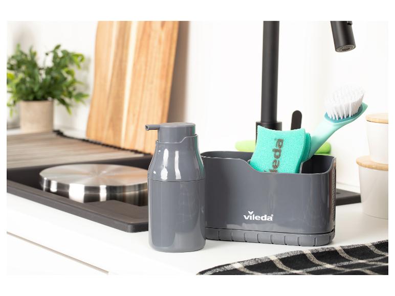 Distributeur de savon gris et brosse à vaisselle avec éponge près de l'évier de cuisine.