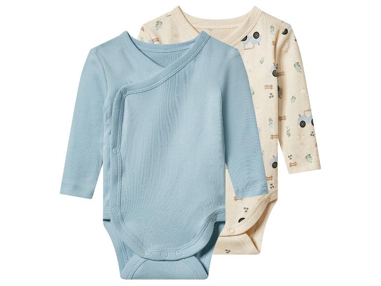 Deux bodies bébé à manches longues : un bleu clair croisé et un beige à motifs de ferme.