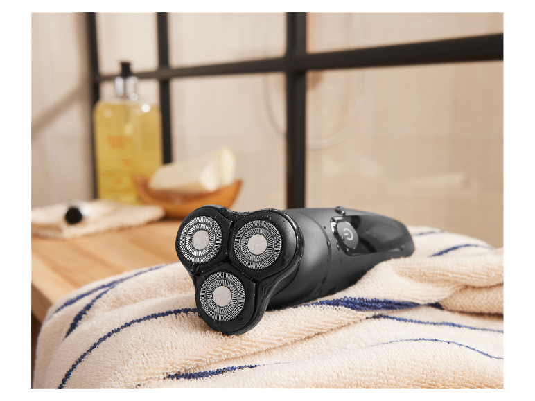 Un rasoir électrique humide repose sur une serviette dans une salle de bain.