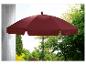Un parasol rouge dans un jardin avec des arbres verts.