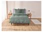 Une couette verte sur un lit avec des tables de chevet en bois.