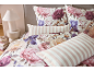 Parure de lit florale avec pivoines et iris, avec oreillers rayés roses et blancs.