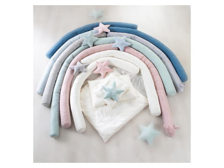Nid de bébé en forme d'arc-en-ciel avec oreillers étoiles et literie blanche.