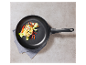 Une poêle noire avec du poulet et des légumes grillés.
