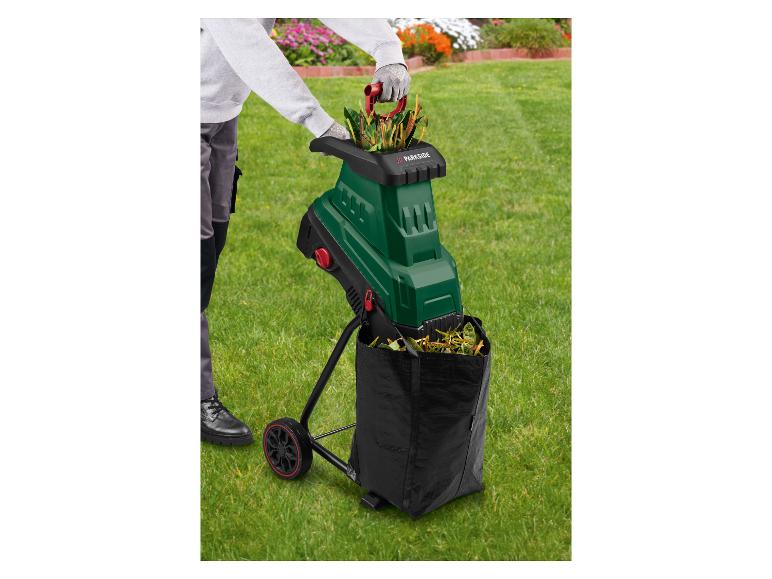Personne dans le jardin utilisant un broyeur de jardin vert avec un sac de collecte noir.