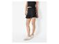 Femme en top noir et jupe-short noire à volants, baskets blanches.