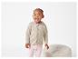 Un bébé portant un cardigan beige en tricot à capuche et un legging rose.