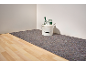 Un seau blanc avec des outils de peinture sur un sous-couche grise sur un plancher de bois clair.
