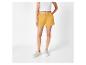 Shorts en mousseline moutarde et baskets blanches.