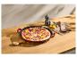 Pizza au salami, oignon rouge et poivrons dans une poêle en fonte sur une table en bois.