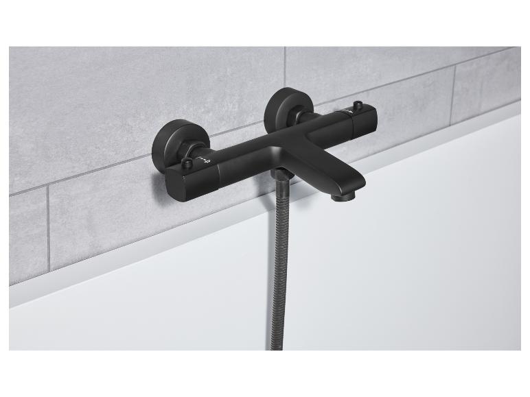 Un robinet de baignoire noir mat avec pomme de douche est monté sur un mur carrelé gris.