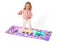 Enfant jouant sur un tapis de piano au sol violet avec des personnages de dessins animés.