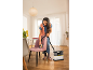 Une femme nettoie une chaise rembourrée rose avec un aspirateur injecteur-extracteur.